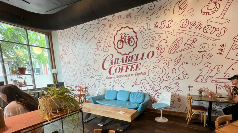 Light blue couch in front of decorated wall that says Carabello Coffee