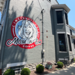 The Mom 'N 'Em face logo on the exterior wall of the Camp Washington location