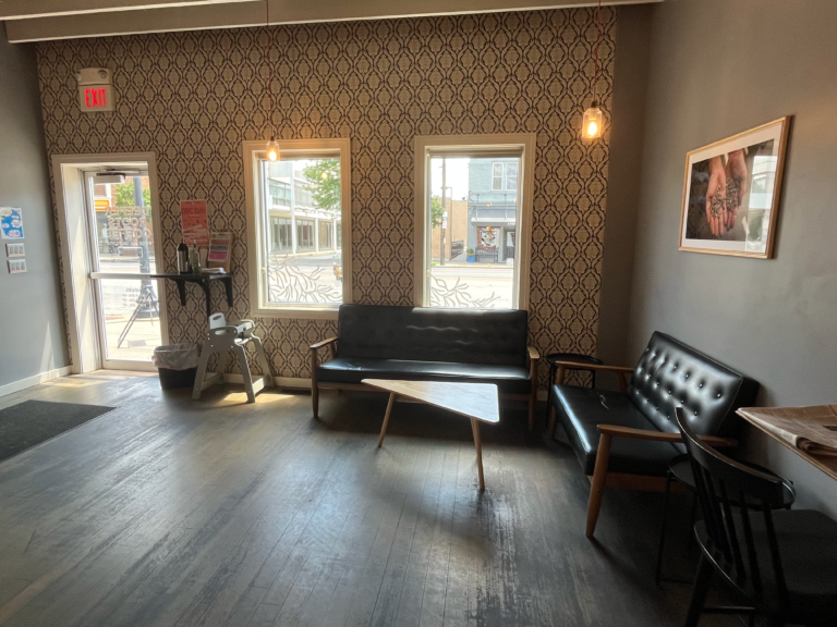 Two leather-cushioned benches around a small triangle coffee table inside Deeper Roots Coffee in Oakley
