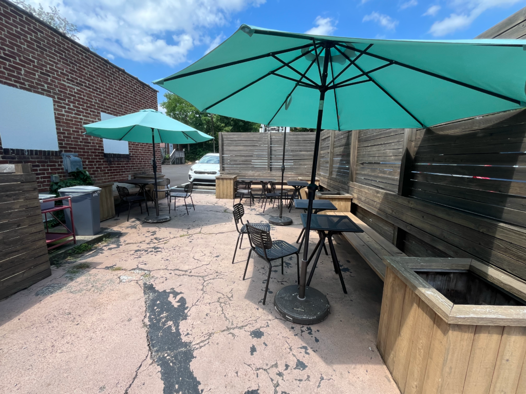 The seating area with large green umbrella tables outside Deeper Roots Coffee in Oakley
