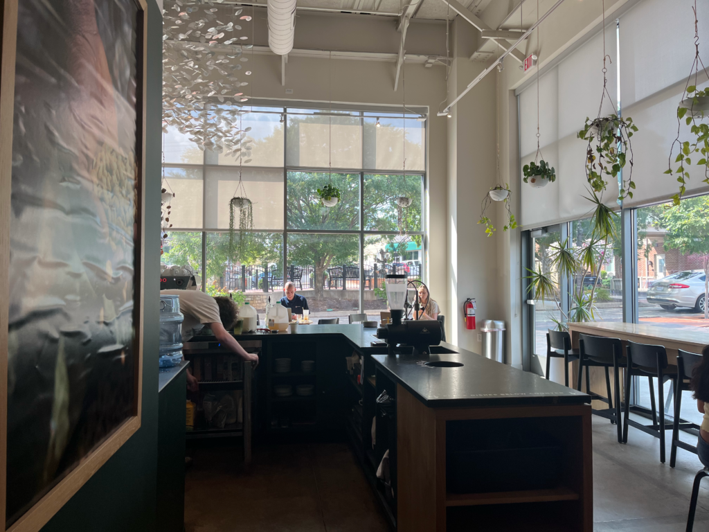 A different angle of the ordering counter and fully-windowed wall inside Deeper Roots Coffee in Montgomery