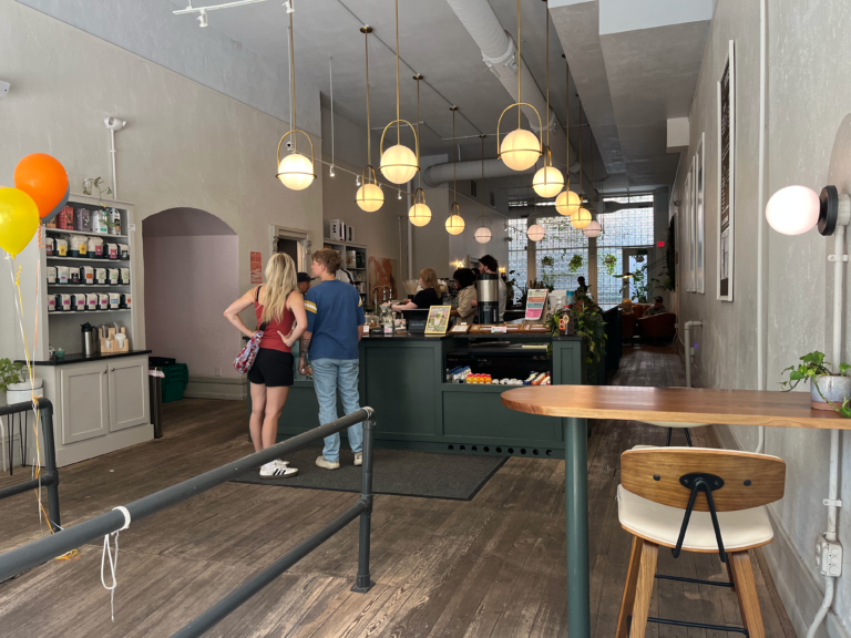 The green ordering counter below spherical hanging light fixtures inside Deeper Roots Coffee on 4th Street