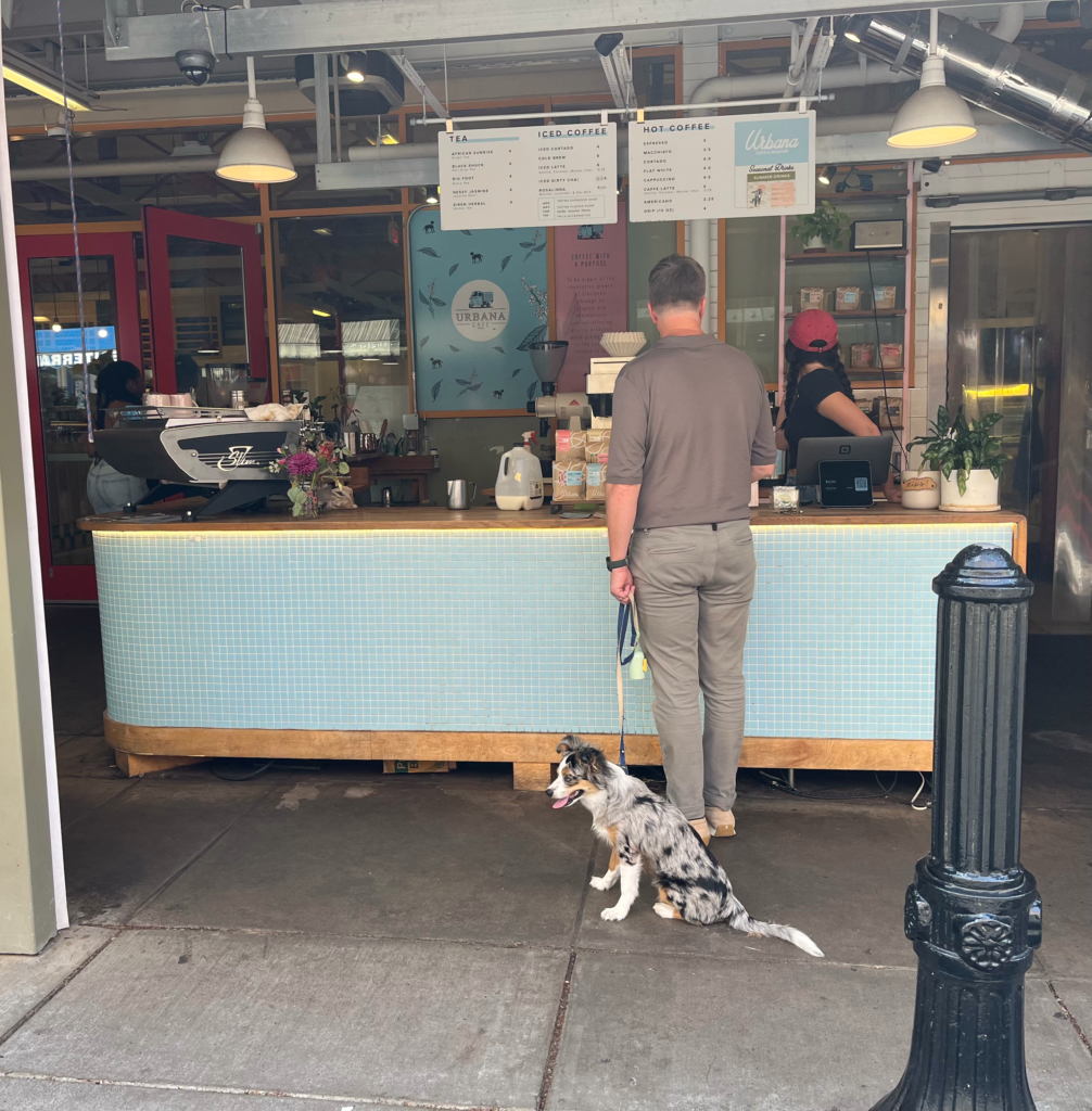 A man with his dog on a leash ordering at the counter of Urbana Cafe at Findlay Market